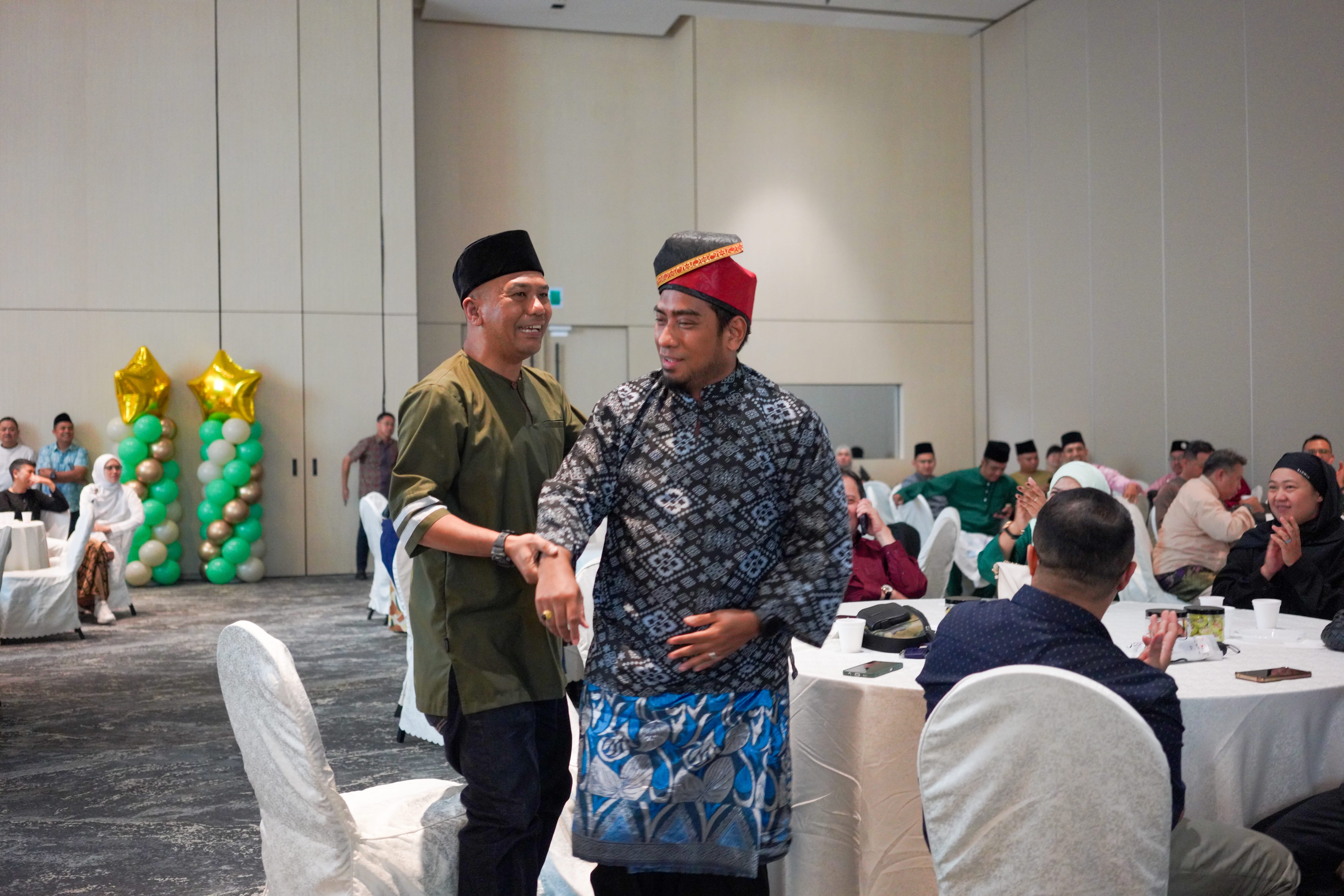Two participants in traditional attire taking part in an interactive programme among banquet tables while guests look on